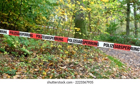 A cordon with red and white police tape and a notice of a police cordon off an area in a forest in autumn in a German forest - Shutterstock ID 2223367935