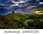 Corfe Castle in the morning with the sun rising through heavy cloud cover
