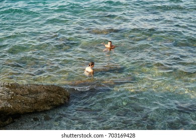 Corfu, Greece - AUGUST 2, 2017: Couple Swimming In The Sea At The Beach