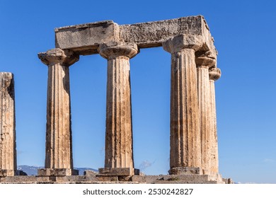 Corinth Temple of Apollo, Ancient ruins with weathered stone columns under a clear blue sky, Greek classical architecture. Corinth, Greece - Powered by Shutterstock