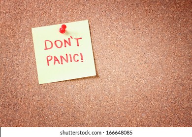 cork board with pinned yellow note and the phrase "dont panic"