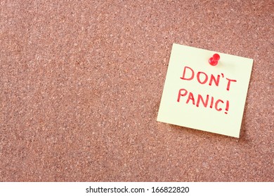 cork board with pinned yellow note and the phrase "dont panic"