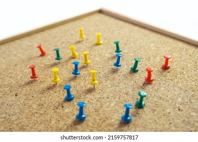 Cork board with scattered around thumbtack isolated on white background, copy space, timber cork pinboard, colorful pin thumbtacks