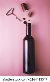 cork from a wine bottle corkscrew shrink wrap and drops of red wine on a pink background. High quality photo