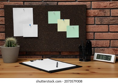 Corkboard With Pinned Notes Hanging On Brick Wall Over Desk In Office