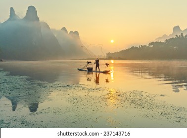 Cormorant fisherman throws a net with ancient bamboo boats at sunrise - Xingping, China - Powered by Shutterstock