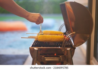 Corn Barbecue With Motion Blur Hand Brush Dipping Sauce On Blur Swimming Pool Party Background