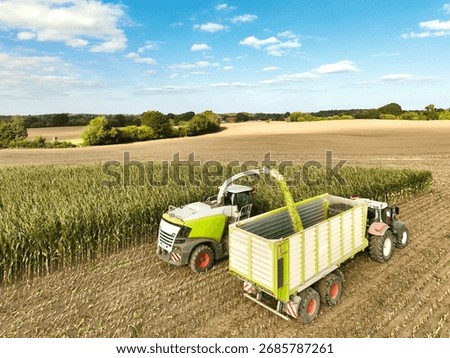 Corn chopper and tractor with loading wagon harvesting in the field - 0161