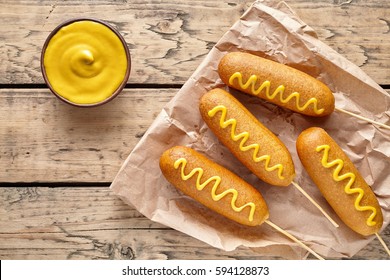 Corn Dog Traditional American Corndog Street Junk Food Deep Fried Hot Dog Meat Sausage With Mustard Snack Treat Coated In A Layer Of Cornmeal Batter On Stick Unhealthy Eating On Rustic Wooden Desk.