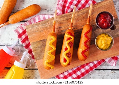 Corn dogs with mustard and ketchup. Top view table scene over a white wood background. - Shutterstock ID 2156075125