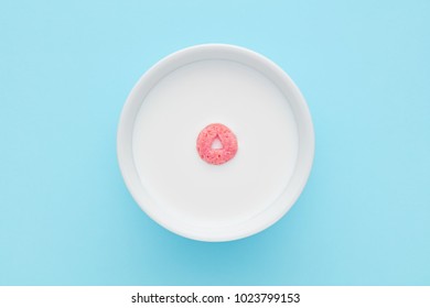 Corn Flakes Cereal Ring Loop Floating On A Bowl Full Of Milk On Blue Background. Top Down Close Up View