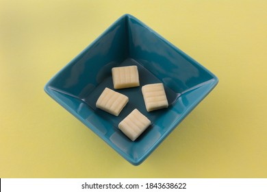 Corn Flavored Hard Candy Chews In Blue Candy Dish On Yellow Background