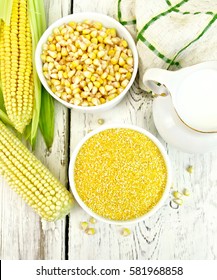 Corn grits and corn in two bowls, a napkin and cobs on the background of the wooden planks on top
