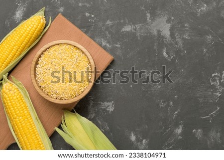 Corn groats with fresh cobs on concrete background, top view