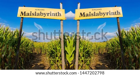 Corn Maze is a maze cut from a corn field. Maize labyrinths are popular with tourists and children. Entrance sign in front of blue sky with lettering in german - entrance Maislabyrinth