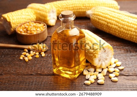 Corn oil, kernels and cobs on wooden table, closeup