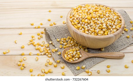 corn seed in wooden bowl and spoon on wooden table background