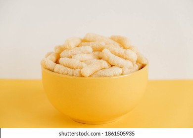 Corn sticks in a yellow bowl on a yellow background. Copy, empty space for text