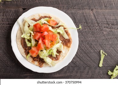 Corn Tortilla Tostada With Refried Beans, Lettuce, Salsa, And Tomatoes Horizontal Top View