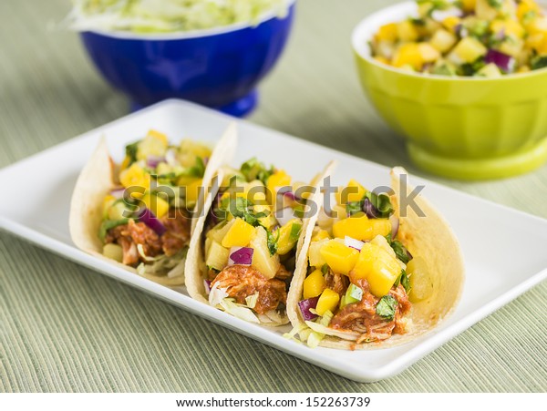 Corn tortillas\
filled with shredded lettuce, shredded barbecue chicken and topped\
with mango pineapple salsa