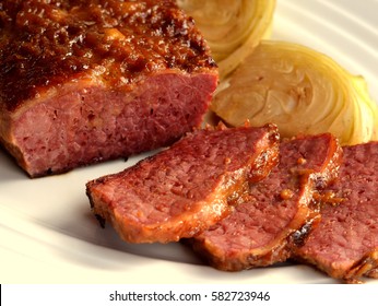 Corned Beef and Cabbage: Traditional Irish Cuisine. Braised and then glazed corned beef served on a white plate with cabbage wedges.