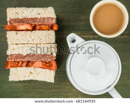 Corned Beef and Tomato White Bread Sandwich Against a Green Background