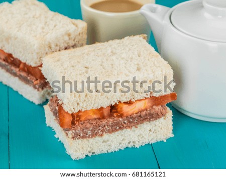 Corned Beef and Tomato White Bread Sandwich Against a Blue Background