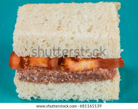 Corned Beef and Tomato White Bread Sandwich Against a Blue Background