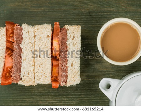 Corned Beef and Tomato White Bread Sandwich Against a Green Background