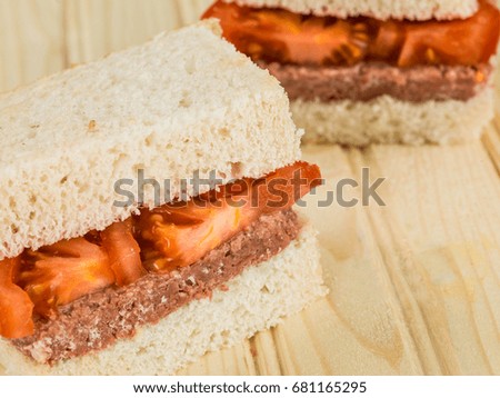 Corned Beef and Tomato White Bread Sandwich Against a Light Wooden Background