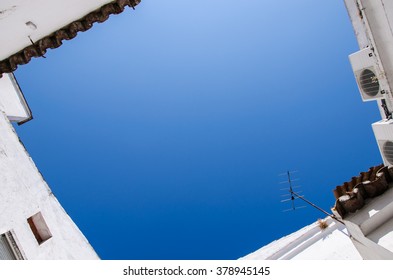 a corner of blue sky surrounded by white house, copy space in the middle