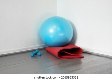 In The Corner Are A Blue Sports Ball And A Red Yoga Mat.