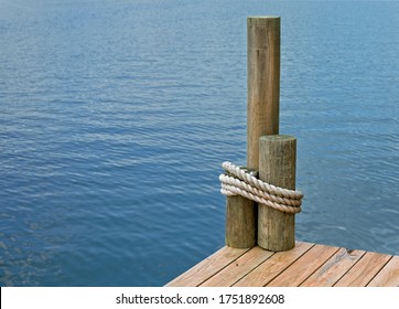 The corner of a boat dock, on a lake, with rope wrapped around pilings.  - Powered by Shutterstock