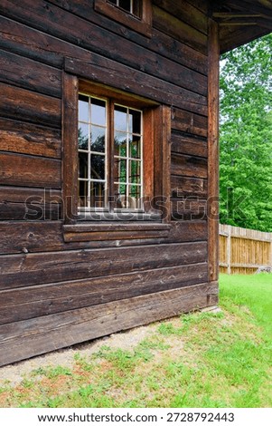 Corner of the building with window made of dark wooden beam