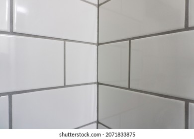 Corner Closeup Of A White Subway Tile Shower With Dark Gray Grout Lines