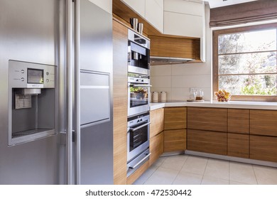 Corner of a freshly-renovated kitchen with wooden cabinet fronts and a side by side refrigerator