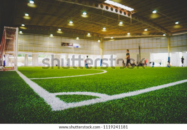 Corner Line of an indoor football soccer\
training field in Junior Soccer Academy school with blurred\
children and coach practicing on the\
background