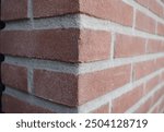 Corner of a masonry construction, a brick wall. Red bricks, grey mortar.