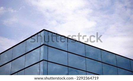 corner of modern facade of glass building against cloudy sky