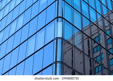 The corner of a modern glass building in Sydney central business district. Reflections of the sky and other buildings are in the glass facade