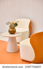 A corner of a modern interior. Two arc - shaped seats in orange color scheme are placed opposite each other. Between them is a round white marble - topped table