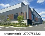 Corner of a modern warehouse unit complex with a foot path, garden and road