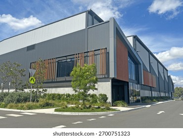 Corner of a modern warehouse unit complex with a foot path, garden and road