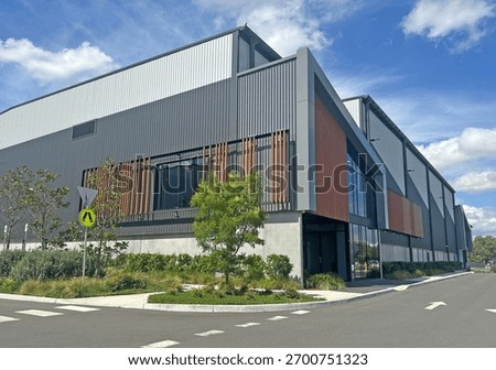Corner of a modern warehouse unit complex with a foot path, garden and road