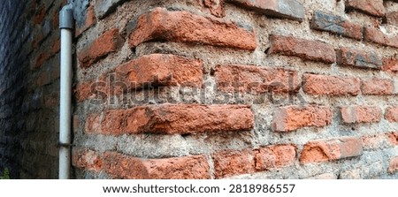 Corner of an old brick wall with a PVC drainage pipe.