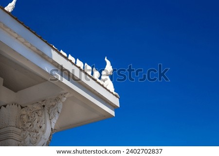 corner of the roof with decoration of the Buddhist white temple Wat Sawang Arom against the sky.