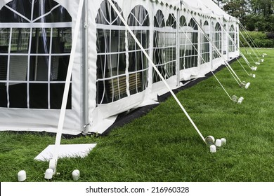 Corner And Side Of Large White Event Tent With Plastic Windows, Anchored On Garden Lawn In Summer