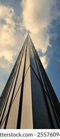 Corner of a skyscraper, bottom view of the sky. Corner building, house, structure, architectural design of urban building with windows. Modern building with windows. Vertical photography, frame.
