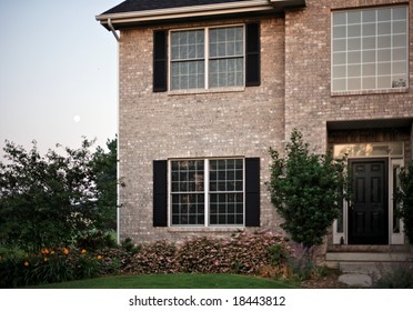 Corner Of Suburban Home With Brick Veneer Facade And Large Energy Efficient Double Pane Windows.