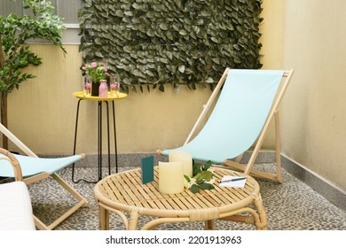 Corner of a terrace with wicker furniture, matching side table and river stone floors